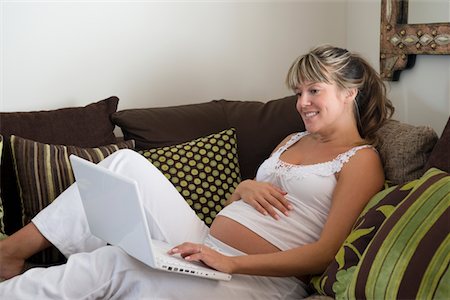 Pregnant woman reclining on sofa with laptop Stock Photo - Premium Royalty-Free, Code: 693-03317778