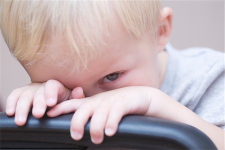 Blonde toddler peeks over chair, looking at camera Stock Photo - Premium Royalty-Free, Code: 693-03317934