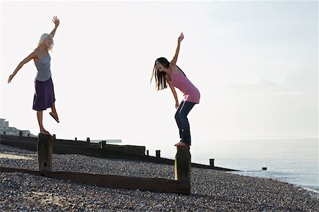 Two young women balancing on wooden wave breakers on beach Stock Photo - Premium Royalty-Free, Code: 693-03310061