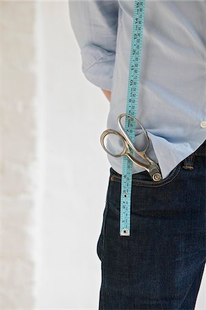 Tailor with scissors in pocket and measuring tape, standing indoors, mid section, close up Stock Photo - Premium Royalty-Free, Code: 693-03310228