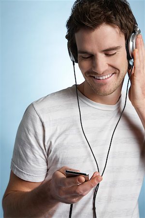 Young man listening to music on headphones Stock Photo - Premium Royalty-Free, Code: 693-03310881