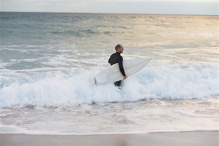 surfer at sunrise - Surfer carrying surfboard in sea, side view Stock Photo - Premium Royalty-Free, Code: 693-03311213