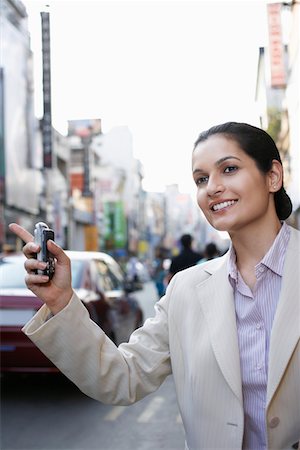 Business woman holding cell phone, hailing taxi Stock Photo - Premium Royalty-Free, Code: 693-03311466