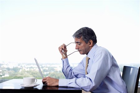 Business man sitting at table, using laptop Foto de stock - Sin royalties Premium, Código: 693-03311496
