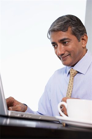 Business man using laptop, smiling, low angle view Stock Photo - Premium Royalty-Free, Code: 693-03311497