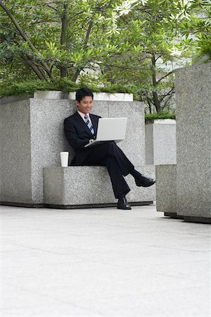 Homme d'affaires de la Chine, Hong Kong, assis sur un banc de pierre à l'aide d'ordinateur portable Photographie de stock - Premium Libres de Droits, Code: 693-03311560