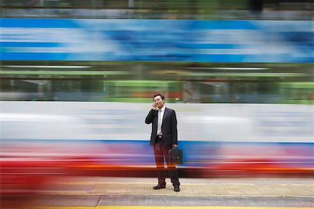 China, Hong Kong, business man using mobile phone, standing on street, long exposure Stock Photo - Premium Royalty-Free, Code: 693-03311562