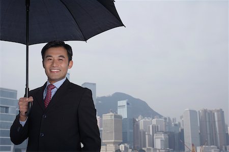 Portrait of business man with umbrella, smiling Stock Photo - Premium Royalty-Free, Code: 693-03311579