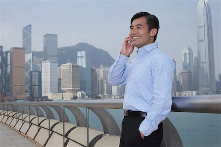 simsearch:693-03307925,k - Young business man on bridge talking on mobile phone, smiling Fotografie stock - Premium Royalty-Free, Codice: 693-03311583