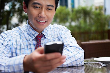 simsearch:693-03311509,k - Business man text messaging sitting in outdoor cafe, close up Stock Photo - Premium Royalty-Free, Code: 693-03311618