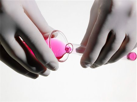 Person wearing rubber gloves pouring pink liquid into vial, close up, studio shot Foto de stock - Sin royalties Premium, Código: 693-03311877