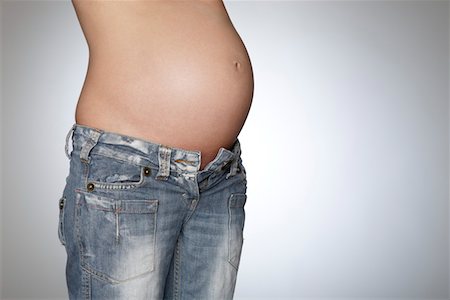 simsearch:693-03315753,k - Pregnant woman wearing jeans, mid section, studio shot Stock Photo - Premium Royalty-Free, Code: 693-03312014
