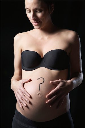 Pregnant woman with question mark on abdomen, studio shot Stock Photo - Premium Royalty-Free, Code: 693-03312031