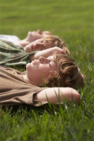 Three teenage brothers (13-17) lying down on front lawn, close up Stock Photo - Premium Royalty-Free, Code: 693-03312105