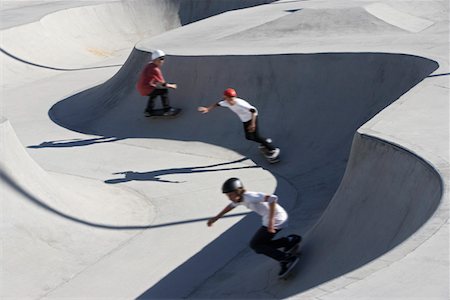 pista de skate - Three teenage boys (16-17) skateboarding at skate park, elevated view Foto de stock - Royalty Free Premium, Número: 693-03312294