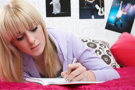 Teenage girl (16-17) lying on bed, writing diary Stock Photo - Premium Royalty-Free, Code: 693-03312464