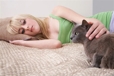 sad person laying down - Teenage girl (16-17) lying on bed with cat Stock Photo - Premium Royalty-Free, Code: 693-03312468