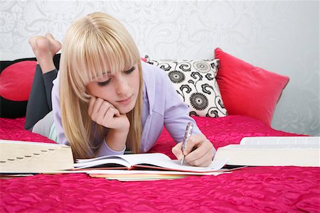 Teenage girl (16-17) lying on bed, writing Stock Photo - Premium Royalty-Free, Code: 693-03312506