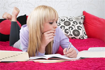 Teenage girl (16-17) lying on bed, writing Stock Photo - Premium Royalty-Free, Code: 693-03312507