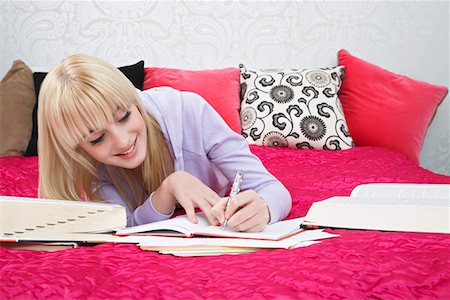 Teenage girl (16-17) lying on bed, writing Stock Photo - Premium Royalty-Free, Code: 693-03312509