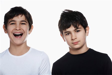 sibling portrait two people serious - Studio portrait of twin boys (13-15), one laughing Stock Photo - Premium Royalty-Free, Code: 693-03312724