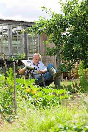 senior man in rubber boots - Senior man pouring drink, sitting in garden Stock Photo - Premium Royalty-Free, Code: 693-03312903