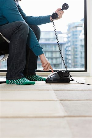 Man dialing phone at home, low section, side view Stock Photo - Premium Royalty-Free, Code: 693-03312940