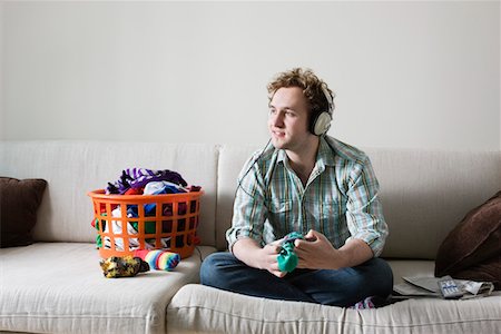 folding - Man folding socks wearing headphones sitting on sofa Stock Photo - Premium Royalty-Free, Code: 693-03312957