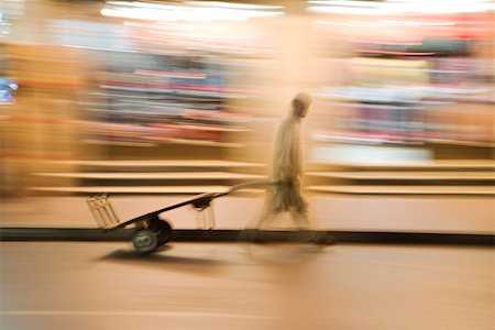 dubai mans - Dubai, UAE, A man wheels an empty cart through the streets of Deira just after dark. Stock Photo - Premium Royalty-Free, Code: 693-03313661