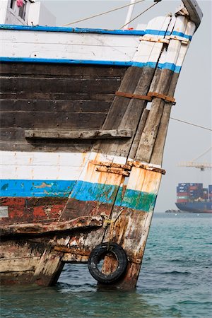 Khor Fakkan, UAE, old wooden dhow washed up on shore in front of Khor Fakkport Stock Photo - Premium Royalty-Free, Code: 693-03313677