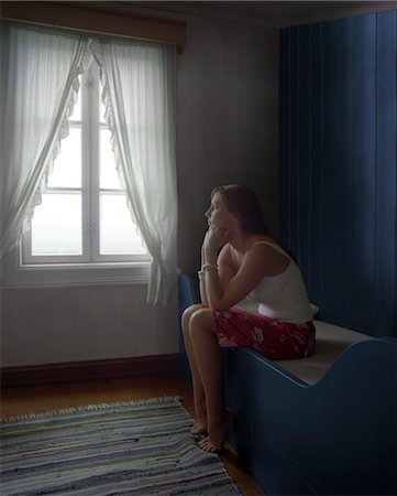 Sad Woman Sitting Alone in Room, daydreaming, side view Stock Photo - Premium Royalty-Free, Code: 693-03363669