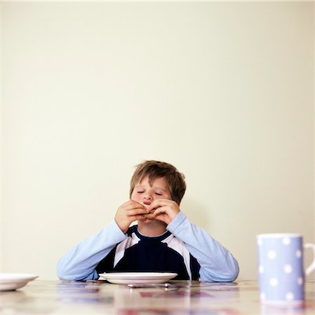 preteen plate - Boy (7-9) eating at table with eyes closed Stock Photo - Premium Royalty-Free, Code: 693-03363754
