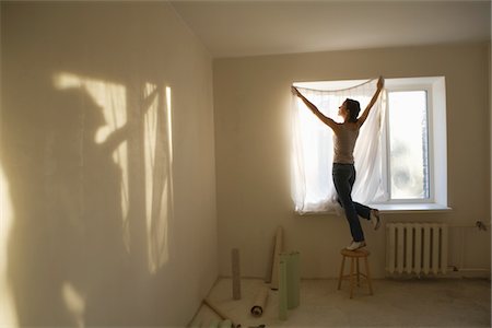 Woman fitting curtains in new apartment Foto de stock - Sin royalties Premium, Código: 693-03440800
