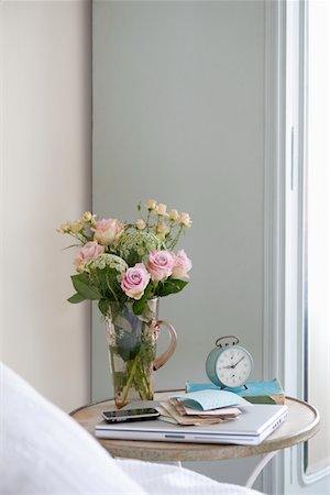 pink summer not flower - Roses in vase on bedside table with books and alarm clock Stock Photo - Premium Royalty-Free, Code: 693-03440873