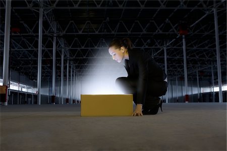 Woman peers into yellow box shining bright light Stock Photo - Premium Royalty-Free, Code: 693-03474172