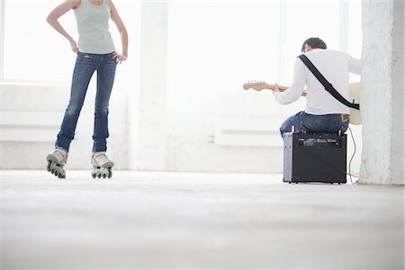 people sitting playing a guitar - Woman on roller skates and man sitting on amp playing electric guitar Stock Photo - Premium Royalty-Free, Code: 693-03474204