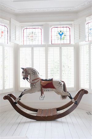 styled interior - Antique rocking horse in bay window with stained glass, London Stock Photo - Premium Royalty-Free, Code: 693-03474274