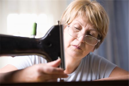 Mature woman adjusts foot of sewing machine Stock Photo - Premium Royalty-Free, Code: 693-03474355