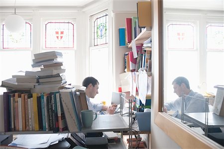 shelf and home - mid adult man working in cluttered study Stock Photo - Premium Royalty-Free, Code: 693-03474486