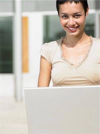 Young woman sitting in plaza courtyard  using laptop, portrait Stock Photo - Premium Royalty-Free, Code: 693-03557263