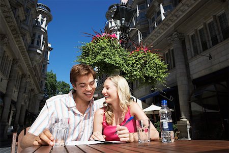 postcard - Young couple sitting at outdoor cafe writing postcard Stock Photo - Premium Royalty-Free, Code: 693-03557304