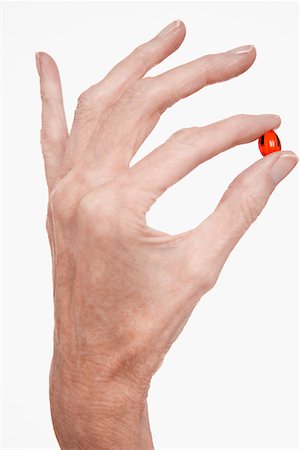 Woman holds red pill between finger and thumb Stock Photo - Premium Royalty-Free, Code: 693-03557413