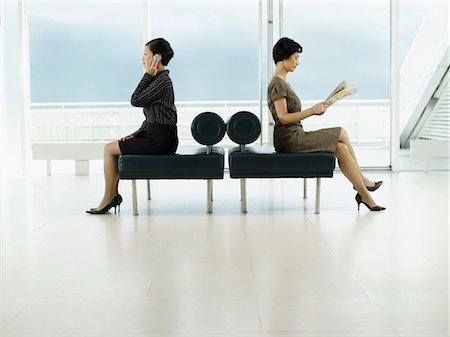 pictures of two people talking at the airport - Businesswomen Sitting on Benches, facing opposite directions, talking on mobile, reading newspaper, profile Stock Photo - Premium Royalty-Free, Code: 693-03557586