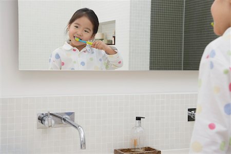 Reflection of Young Girl in pyjamas Brushing Her Teeth Stock Photo - Premium Royalty-Free, Code: 693-03557641