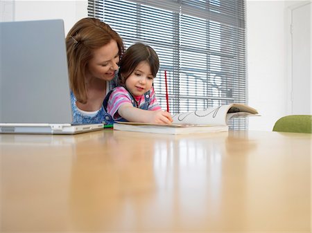 Girl (3-4) colouring in book beside mother using laptop, in home Stock Photo - Premium Royalty-Free, Code: 693-03564356