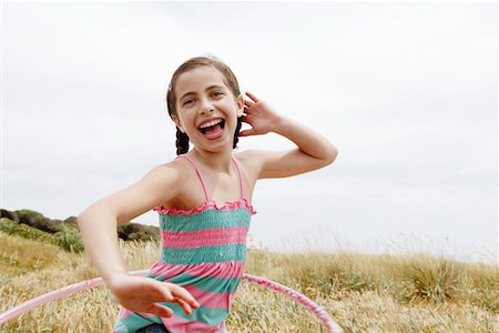Smiling, pre-teen Girl Hula Hooping in field Stock Photo - Premium Royalty-Free, Code: 693-03564598