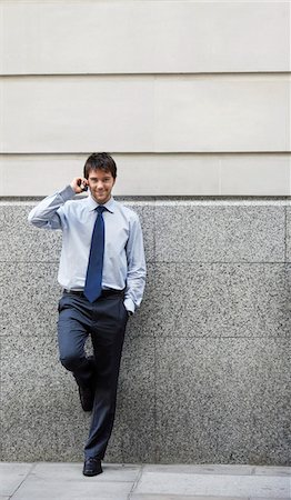 simsearch:693-03307925,k - Businessman on cell phone leaning on wall of building Fotografie stock - Premium Royalty-Free, Codice: 693-03564873