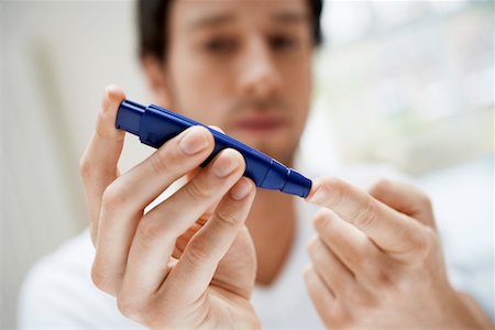 exames de sangue - Man using lancelet on finger in bathroom, close up Foto de stock - Royalty Free Premium, Número: 693-03564888