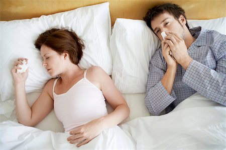 Couple with Colds Lying in Bed, high angle view Stock Photo - Premium Royalty-Free, Code: 693-03564922