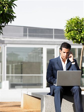 simsearch:693-03303406,k - Businessman sitting alone in plaza using laptop and cell phone Foto de stock - Sin royalties Premium, Código: 693-03564944